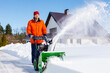 © gankevstock - Happy man clearing deep snow from a driveway with a snow blower on a bright winter day