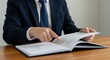 © Strive Studio - Person in suit reading a document at a wooden desk.