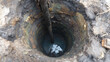 © noiteterna - Pozo profundo excavado manualmente con agua en el fondo y estratos visibles de tierra y roca. Ideal para estudios geotécnicos, captación de agua subterránea o análisis de composición del terreno.