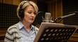 © Image - Woman with headphones recording voiceover in a studio. Professional sound booth setting.