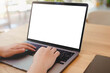 © Thaspol - A person's hands typing on a laptop with a blank white screen in a bright, modern office or cafe. A versatile mockup for remote work, business, or education.