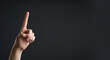 © farah - Hand gesturing pointing upwards on a dark background with copy space
