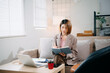 © laddawan - young attrative asian female working at home hand use tablet checking businesss data chart planning report with leisure relax on sofa