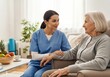 © WisChi - A caregiver in blue scrubs talks with an elderly woman in a comfortable chair