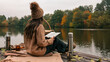© shine.graphics - Woman enjoying a book by the lake on a cozy autumn day