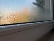 © Siti Fatonah - Close-up photo of condensation and water droplets on window glass in cold weather with blurred autumn landscape in the background. Great for weather, home comfort, or seasonal mood imagery