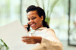 © bnenin - African-American Woman Talking On Phone While Reviewing Paper In Bright Modern Office