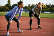 © djile - Two diverse women athletes taking a break on an athletic track after a training session