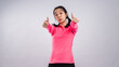 © Daniel - Asian woman in a bright pink long-sleeve sports shirt and black shorts standing confidently against a plain white background, smiling and showing a thumbs-up gesture straight toward the camera