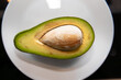 © Inna Nikitina - Whole and cut avocados on a wooden table, close-up. Avocado on a white plate. Avocado fruit. Raw fruit is a healthy green food.