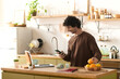 © LIGHTFIELD STUDIOS - Young handsome man enjoys a moment in a bright kitchen while checking his phone