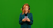 © RecCameraStock - Woman listening to something new in headphones and moving in the rhythm in big black headphones using smartphone. Green screen display and woman using gadgets.