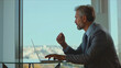 © Videophilia - Experienced senior corporate leader diligently typing on a laptop, reflecting expertise and professionalism while staying connected in a bright contemporary office with a city view