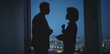 © Videophilia - Two business professionals in sharp silhouette are having an intense discussion near a large window, with blurred city lights visible in the distant night background