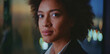 © Videophilia - Confident businesswoman wearing a suit and having afro hair. Looking directly at the camera with city lights blurred in the background. Representing determination and success in an urban night setting