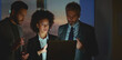 © Videophilia - Diverse business professionals working together in a corporate office, a dedicated team collaborating after hours, focusing on a laptop screen to meet deadlines and drive project success