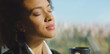 © Videophilia - Black woman with eyes closed savoring a warm cup of coffee in soft sunlight, enjoying a peaceful, mindful moment of calm and cozy rest at home or office window