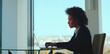 © Videophilia - Black businesswoman typing on laptop in a high-rise office with sweeping city skyline view, focused and professional, embodying dedication, leadership and modern corporate ambition