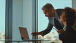 © Videophilia - Diverse business professionals collaborate in a bright modern office, experienced man points at laptop while mentoring a smiling young woman, teamwork and knowledge sharing