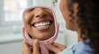 © rdkcho - Close-up of happy woman examining her perfect white smile reflected in a small pink mirror at the dental clinic.