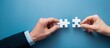 © Di - Two hands connecting two intricately designed puzzle pieces, illustrates the powerful concept of collaboration and teamwork in a professional setting, achieve goals and success in business endeavors.