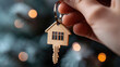 © syhin_stas - Person's hand extending keys and a house-shaped keychain, signifying themes of buying a new home, securing property, future home plans, or a special Christmas present