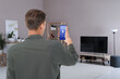 © New Africa - Man using smart home app on mobile phone to control house features