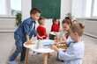 © New Africa - Cute children at white tables during lesson in elementary school