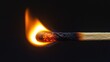 © vadosloginov - Close-up view of a match igniting with a bright flame against a dark background