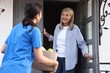 © New Africa - Humanitarian aid for elderly people. Volunteer holding cardboard box with food products and senior woman near door outdoors