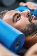 © Konstiantyn Zapylaie - Young caucasian male relaxing on foam roller in gym setting