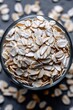 © Konstiantyn Zapylaie - Close-up of raw rolled oats in a glass bowl on dark surface