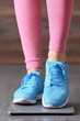 © Konstiantyn Zapylaie - Close-up of person in pink leggings and blue sneakers on scale