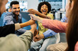 © Xavier Lorenzo - Group of multiracial business colleagues laughing and joining fists together while celebrating at a modern office, showing motivation, friendship, and teamwork. Collaboration and unity concept.