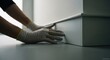 © mlangsen - Close-up of gloved hands examining a pristine white baseboard installation indoors