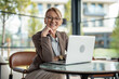 © Jelena - Confident mature businesswoman smiling working on laptop