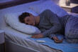 © Pixel-Shot - Young man sleeping on electric heating pad in bedroom at night