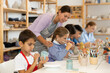© JackF - Focused boy paints a mug made of clay at a workshop. Boy at a children's master class on ceramics next to a teacher