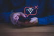© ParinPIX - Close-up of hand holding smartphone with no Wi-Fi connection icon, symbolizing internet disconnection, network error, or poor signal, connectivity issues, technology problem, online failure concept.