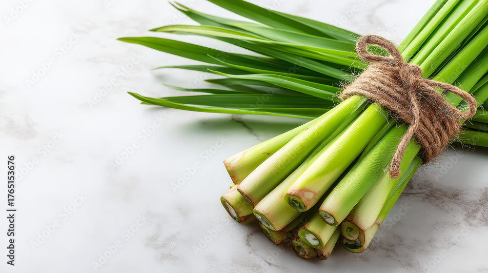 A bunch of green herbs are tied together. The herbs are fresh and green, and they are arranged in a neat bundle. The bundle is placed on a white surface, which gives the herbs a clean