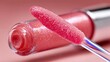 © Nasr - A closeup shot of a lip gloss applicator, coated with a shimmering, light pink gloss, resting against the tube against a soft pink background