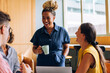 © (JLco) Julia Amaral - Smiling colleagues sharing a conversation during a casual workspace moment together
