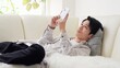 © mapo - 寝ながらスマホを見るアジア人男性