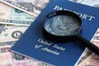 © mehaniq41 - US passport and magnifying glass on the background of many dollar bills close up