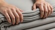 © photoplotnikov - Female hands folding gray blanket for neat storage