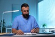 © New Africa - Doctor writing notes at table in clinic during night shift