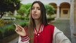 © Krakenimages.com - Woman in red cheerleader uniform points index finger outside an old university building; skepticism.