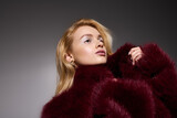 Stylish blonde woman in a striking red fur coat during a fashionable winter scene