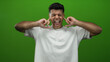 © Krakenimages.com - Young man in white shirt with facial expressions covering ears against green background isolated