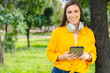 © alfons - Happy woman wearing yellow shirt holding digital tablet and smiling outdoors in sunny green park with copy space,technology and lifestyle concept, natural background for design or promotional template